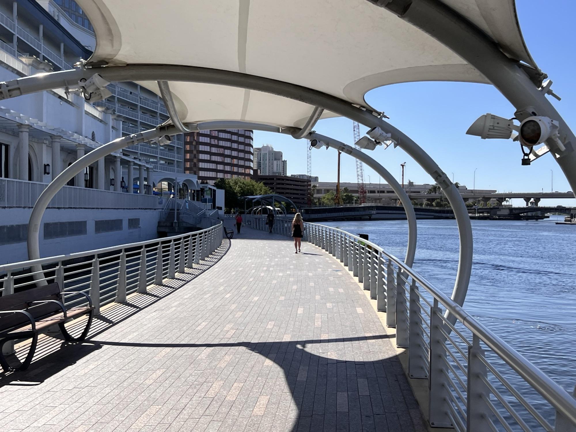 A shaded stretch of the Tampa Riverwalk along the Hillsborough River
